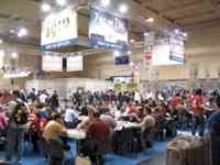 Large room with many people playing games at tables under Days of Wonder signs