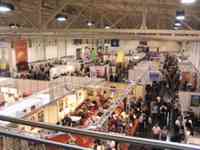 Overview of large room divided into sections and stalls and aisles, with many people walking and playing at tables